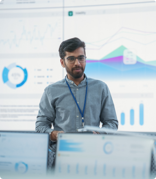 man talking to a room of people using multiple graphs and tables